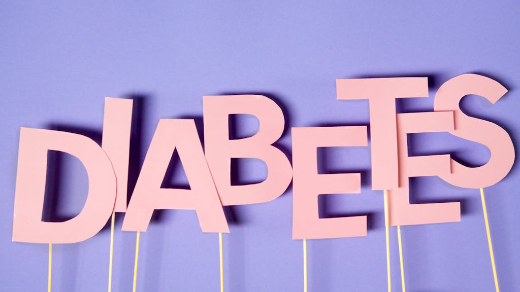 Creative conceptual image of diabetes awareness with pink letters on purple background.